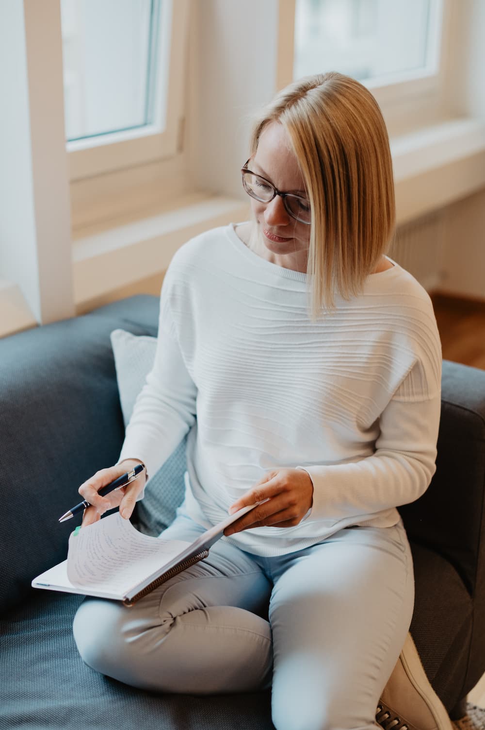 Maria Kosmala sitzt entspannt auf dem Sofa, schreibt reflektierend in ihr Notizbuch – ein Moment der Selbstforschung und Klarheit, der ihre Verbindung von Coaching, Bazi Suanming und täglichem Forschen sichtbar macht.